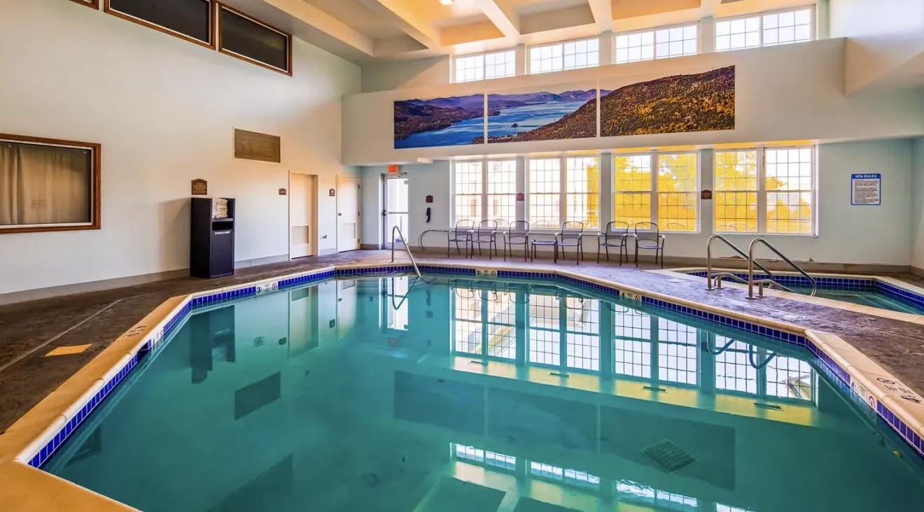 A large indoor swimming pool with windows looking out over fall foliage.